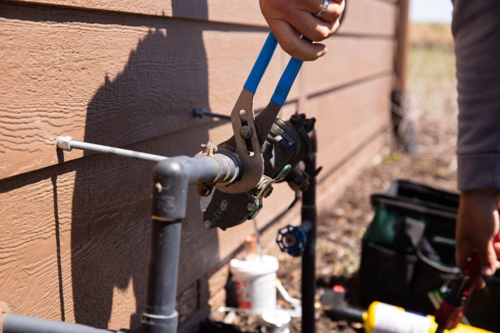 Technician performing irrigation repair on a lawn sprinkler system in Omaha.