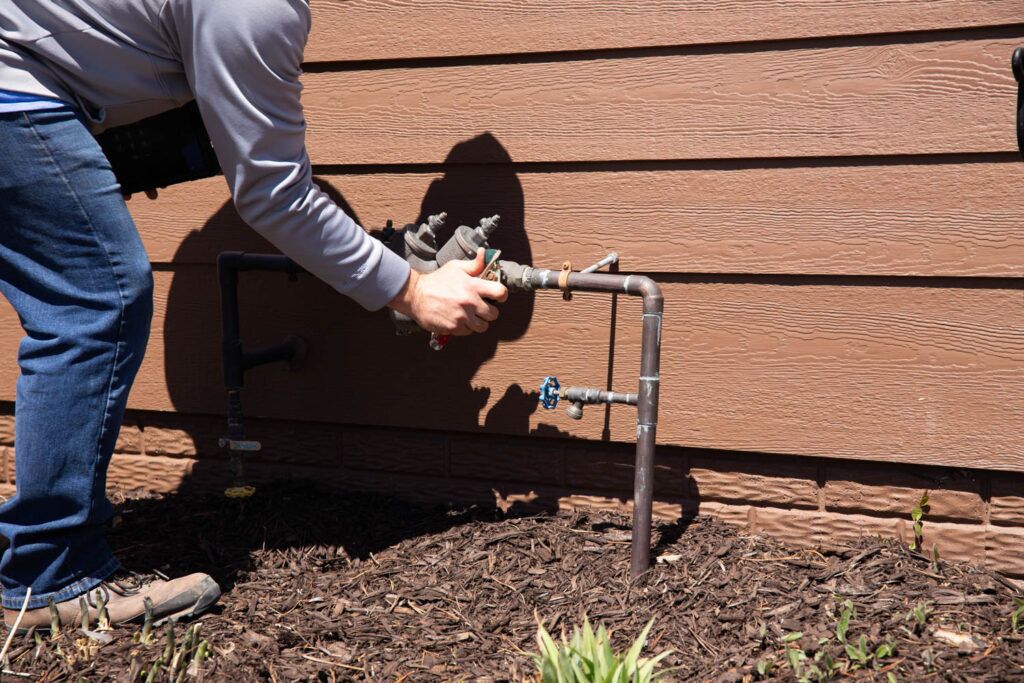 Technician performing sprinkler repair in Omaha lawn during irrigation service visit